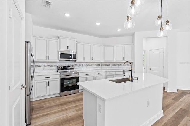 kitchen featuring appliances with stainless steel finishes, a sink, light wood finished floors, decorative backsplash, and recessed lighting
