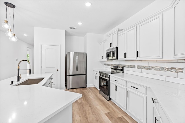 kitchen with stainless steel appliances, a sink, tasteful backsplash, light wood-style floors, and recessed lighting