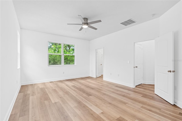 spare room with ceiling fan, light wood-type flooring, and baseboards