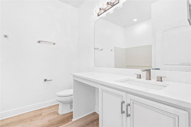 bathroom with wood finished floors, toilet, vanity, and baseboards