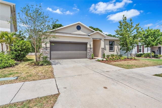 single story home with stucco siding, stone siding, a garage, and concrete driveway