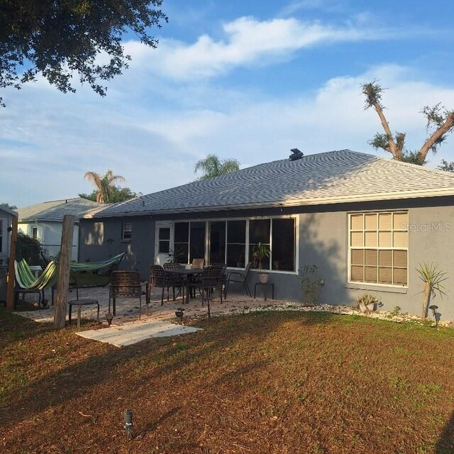 37535 Laurel Hammock Dr, Zephyrhills, FL 33541 - rear view of house featuring stucco siding, a shingled roof, a patio area, and a lawn