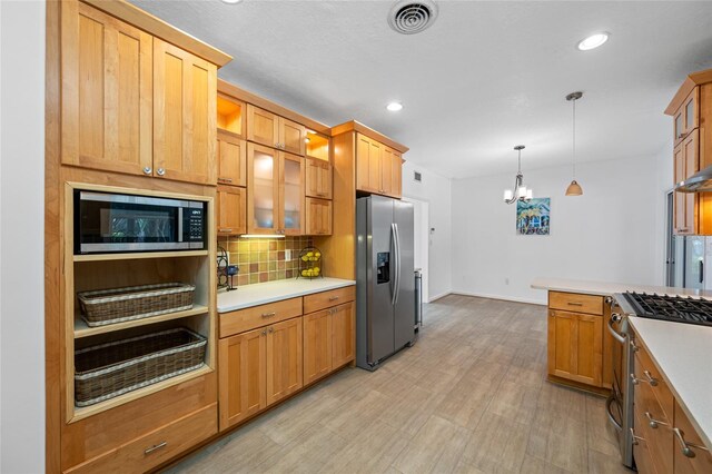 401 Whitcomb Blvd, Tarpon Springs, FL 34689 - kitchen with appliances with stainless steel finishes, a chandelier, tasteful backsplash, glass insert cabinets, and light countertops