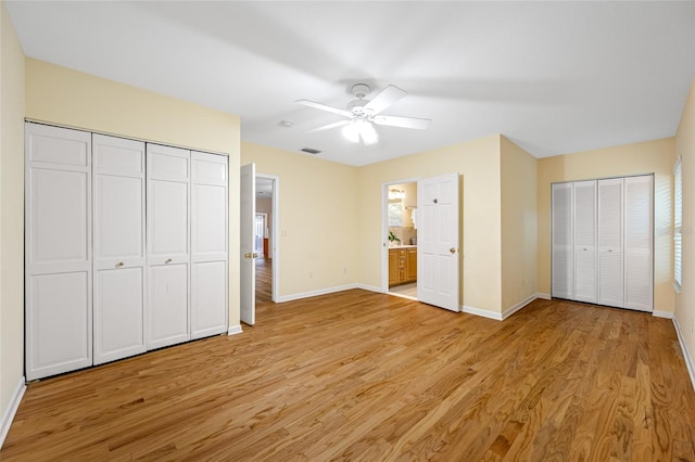 401 Whitcomb Blvd, Tarpon Springs, FL 34689 - unfurnished bedroom with baseboards, light wood-type flooring, two closets, a ceiling fan, and ensuite bath