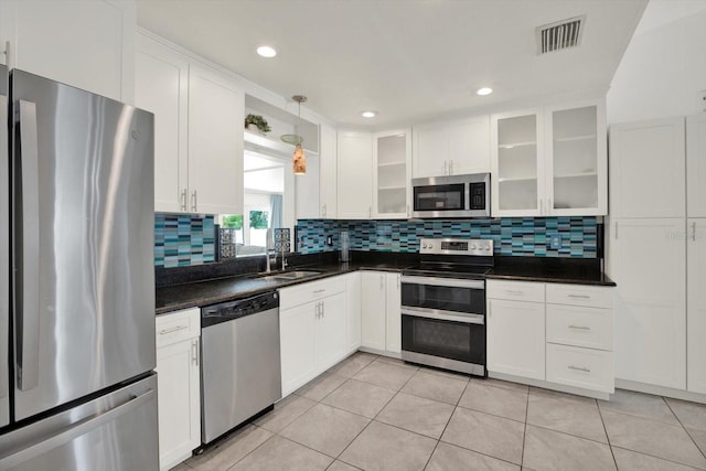 5875 Darren Ct N, Clearwater, FL 33760 - kitchen with stainless steel appliances, a sink, white cabinetry, tasteful backsplash, and dark countertops
