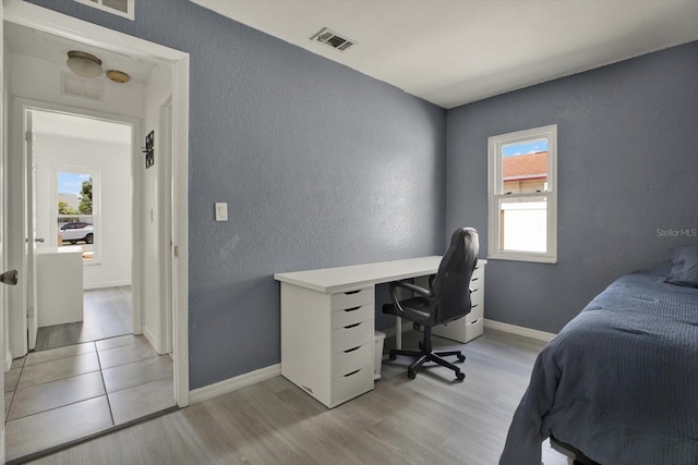 5875 Darren Ct N, Clearwater, FL 33760 - bedroom featuring a textured wall, light wood-style floors, an office area, and baseboards