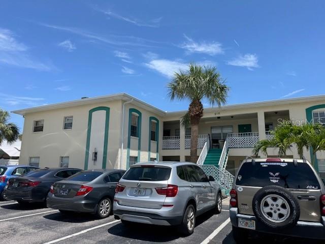 510 70th Ave, St Pete Beach, FL 33706 - view of front of property featuring stucco siding, uncovered parking, and stairway