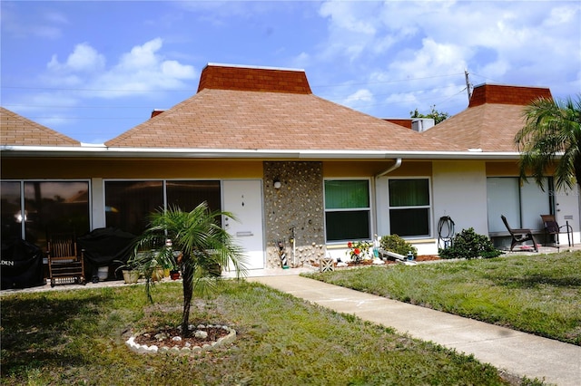 view of front of house with roof with shingles, a chimney, a front lawn, and stucco siding