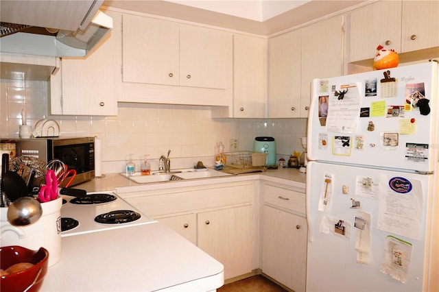 kitchen with freestanding refrigerator, stainless steel microwave, under cabinet range hood, a sink, and light countertops