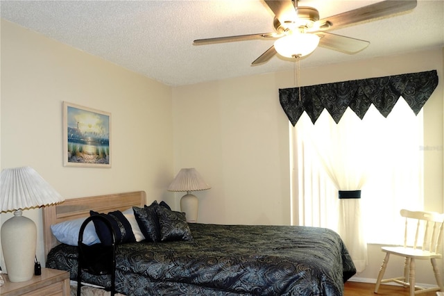 bedroom with a textured ceiling, a ceiling fan, and wood finished floors