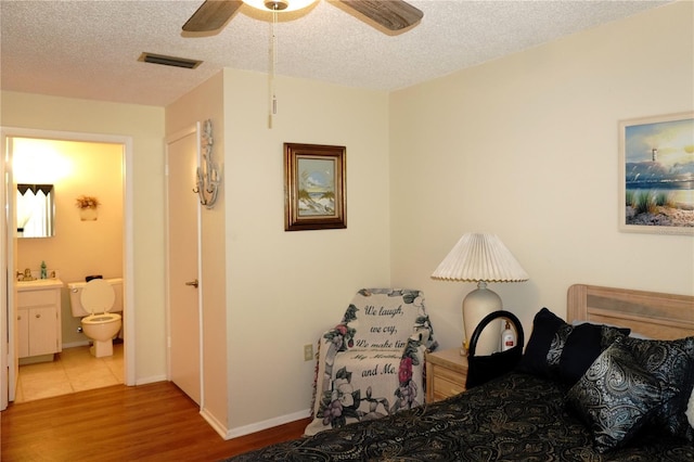 bedroom with wood finished floors, connected bathroom, a textured ceiling, a ceiling fan, and baseboards