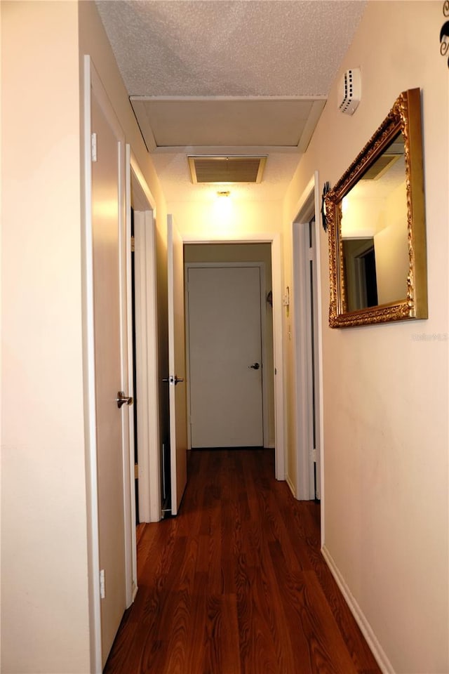 corridor featuring attic access and dark wood-style floors