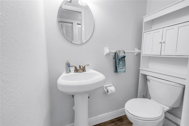 7801 11th St N Unit 104, Saint Petersburg, FL 33702 - half bathroom featuring baseboards, toilet, and wood finished floors