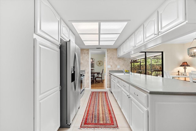 535 Sandy Hook, Palm Harbor, FL 34683 - kitchen featuring stainless steel fridge with ice dispenser, white cabinetry, a sink, light tile patterned floors, and a peninsula