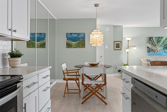 dining room with light wood-style floors, a chandelier, and baseboards