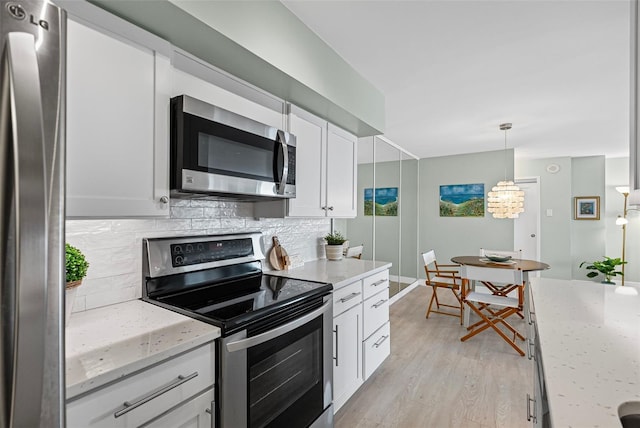 kitchen featuring appliances with stainless steel finishes, backsplash, light wood finished floors, white cabinets, and light stone counters