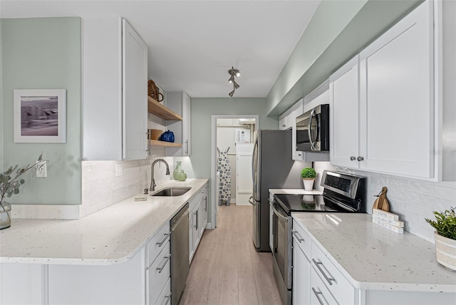 kitchen featuring appliances with stainless steel finishes, a sink, open shelves, decorative backsplash, and white cabinets