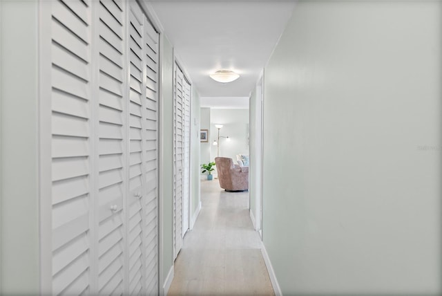 hallway featuring light wood-type flooring and baseboards