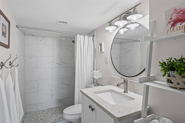 full bathroom with toilet, tiled shower, and vanity
