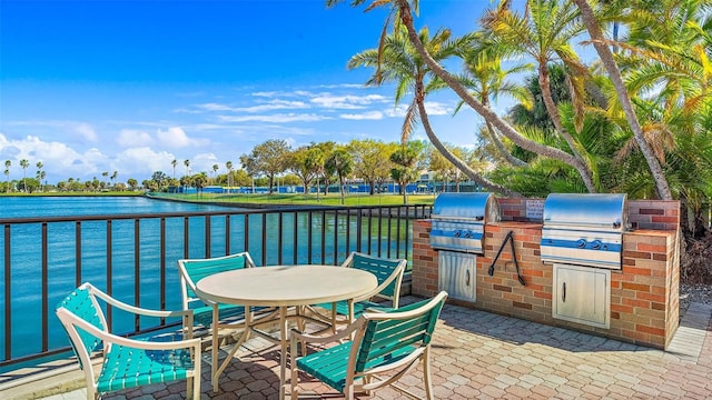 view of patio / terrace featuring exterior kitchen, a grill, and a water view