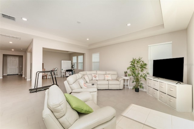 living area featuring baseboards, a raised ceiling, light tile patterned floors, and recessed lighting