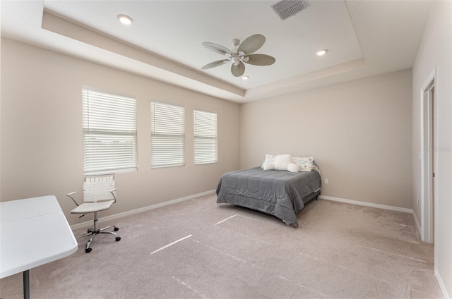carpeted bedroom with a tray ceiling, baseboards, recessed lighting, and ceiling fan