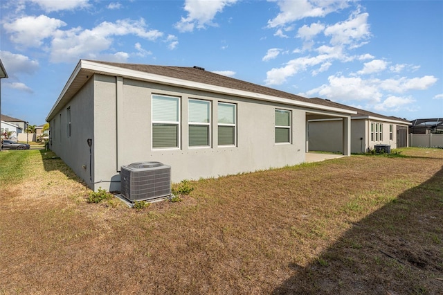 back of property featuring central AC unit, a lawn, and stucco siding