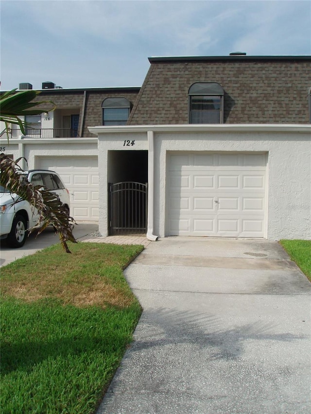 2980 Haines Bayshore Rd Unit 124, Clearwater, FL 33760 - townhome / multi-family property with mansard roof, roof with shingles, stucco siding, driveway, and a garage