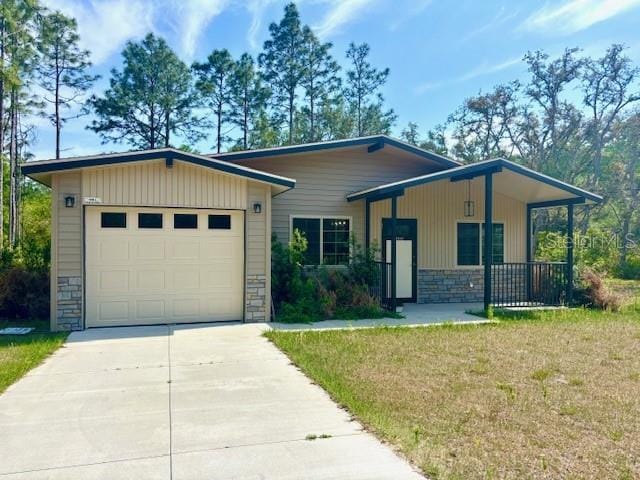 6906 W Barbara Ann Ln, Homosassa, FL 34446 - view of front of property featuring stone siding, concrete driveway, a garage, and a front lawn