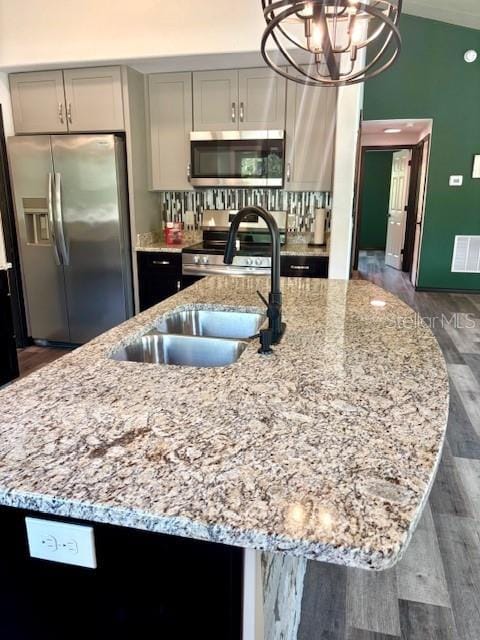 6906 W Barbara Ann Ln, Homosassa, FL 34446 - kitchen with stainless steel appliances, light stone countertops, a chandelier, and dark wood-type flooring