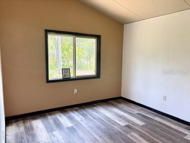 6906 W Barbara Ann Ln, Homosassa, FL 34446 - unfurnished room with wood finished floors, vaulted ceiling, and baseboards