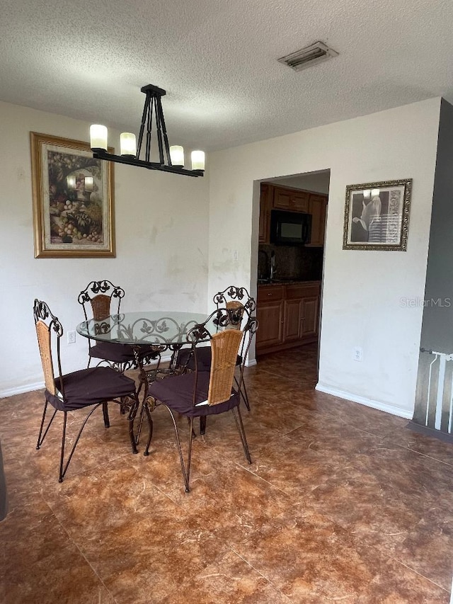 dining space with a chandelier, a textured ceiling, and dark flooring