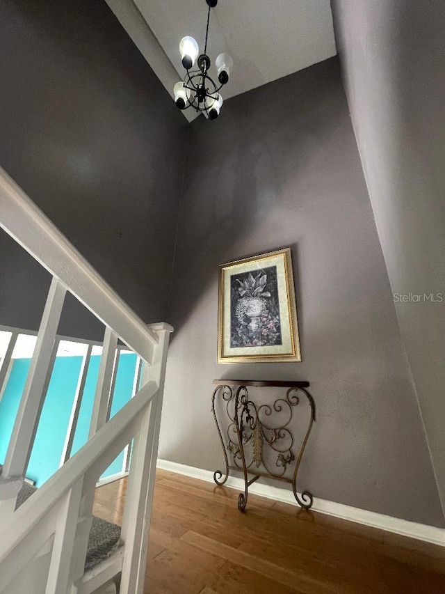 staircase with wood finished floors, a chandelier, and baseboards