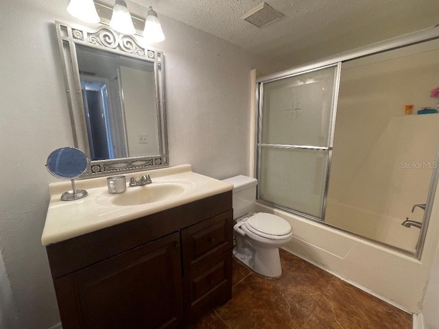 bathroom featuring a textured ceiling, a textured wall, vanity, toilet, and shower / bath combination with glass door