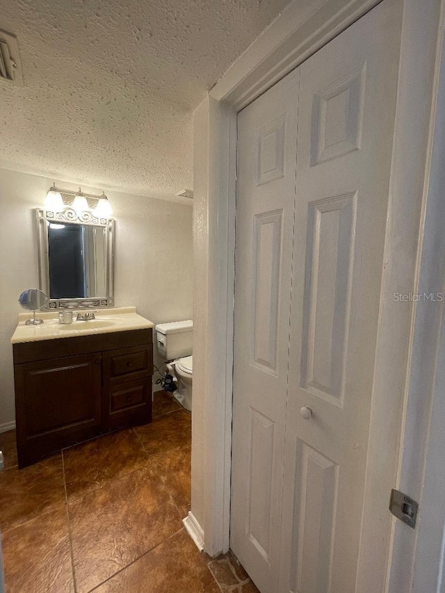 bathroom featuring a textured ceiling, toilet, vanity, and tile patterned floors