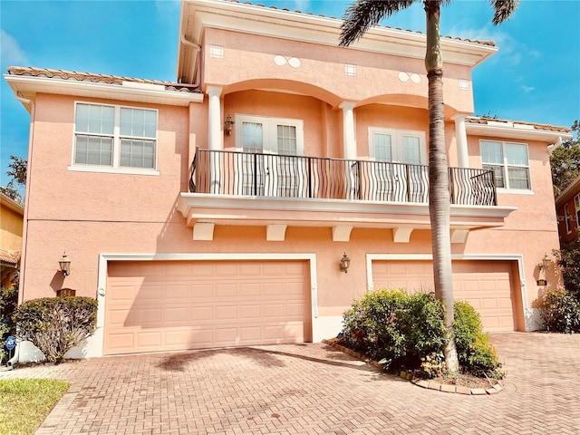 184 Banyan Bay Dr, Saint Petersburg, FL 33705 - view of front of home featuring a balcony, a garage, decorative driveway, and stucco siding