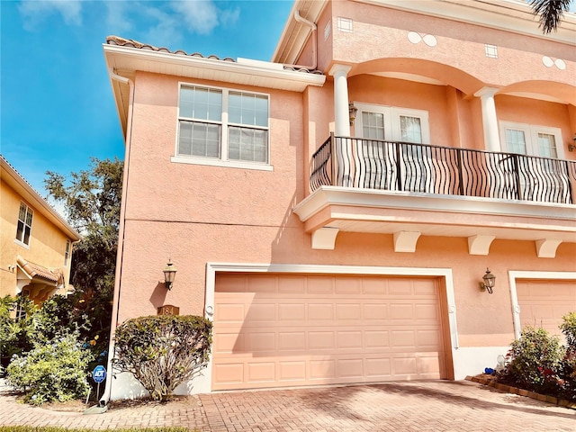 184 Banyan Bay Dr, Saint Petersburg, FL 33705 - view of front of property featuring a balcony, stucco siding, a garage, and decorative driveway