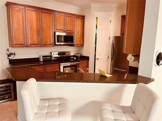 184 Banyan Bay Dr, Saint Petersburg, FL 33705 - kitchen featuring stainless steel appliances, crown molding, a peninsula, brown cabinets, and a breakfast bar