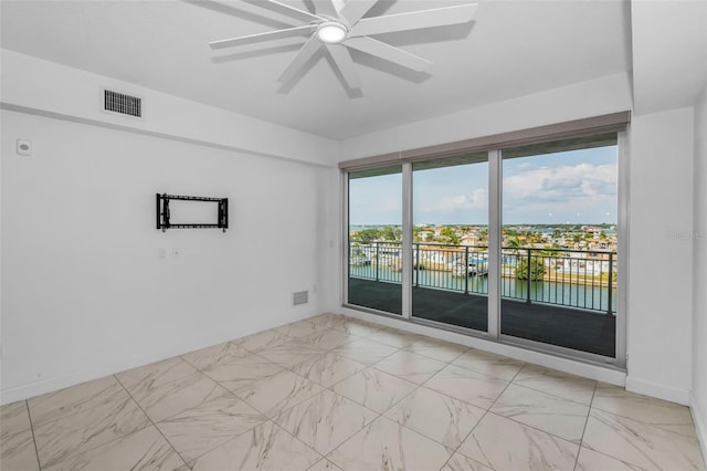 unfurnished room featuring a water view, ceiling fan, and light marble finish floors