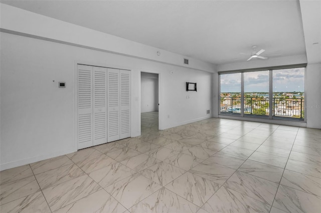 spare room with marble finish floors, ceiling fan, and baseboards