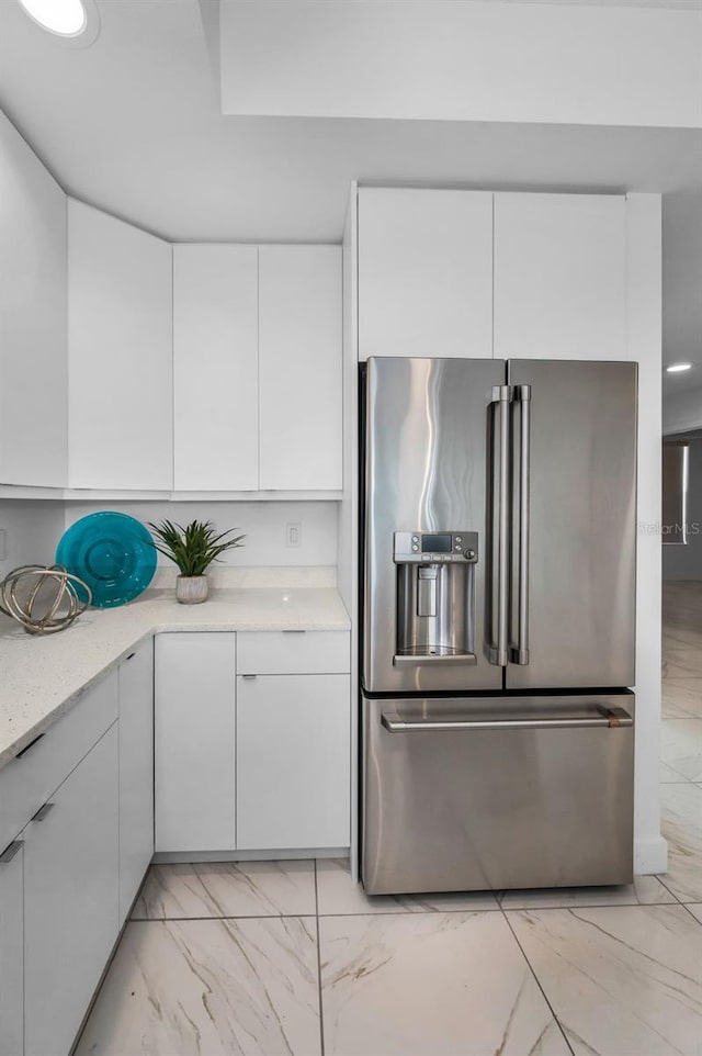 kitchen featuring high quality fridge, light marble finish floors, white cabinetry, modern cabinets, and light stone countertops