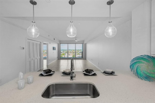 kitchen featuring a sink, pendant lighting, open floor plan, baseboards, and light stone countertops