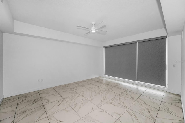 unfurnished room with marble finish floors, ceiling fan, and baseboards