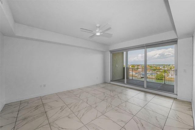 spare room featuring marble look tile flooring and a ceiling fan