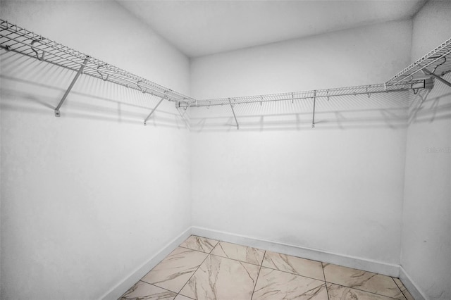 spacious closet featuring light marble finish flooring