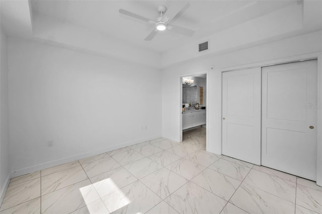 unfurnished bedroom featuring light marble finish floors, baseboards, a closet, and ensuite bathroom
