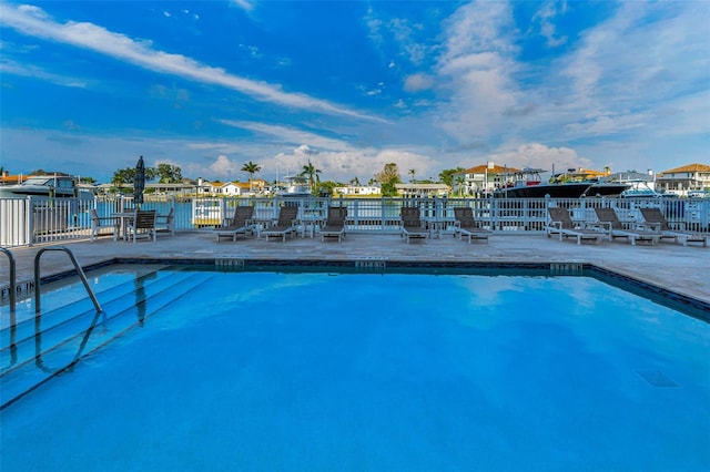 community pool with a patio area and fence