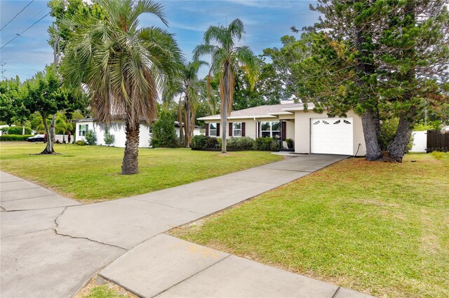 119 N Hillcrest Ave, Clearwater, FL 33755 - view of front of home with concrete driveway, an attached garage, a front yard, and stucco siding