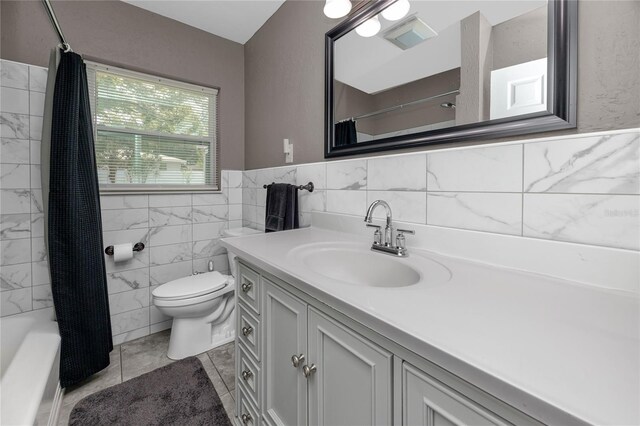 119 N Hillcrest Ave, Clearwater, FL 33755 - bathroom with toilet, vanity, tile walls, wainscoting, and shower / bath combination with curtain