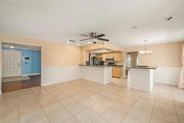 16201 Country Crossing Dr, Tampa, FL 33624 - kitchen featuring stainless steel appliances, a peninsula, a chandelier, wainscoting, and dark countertops